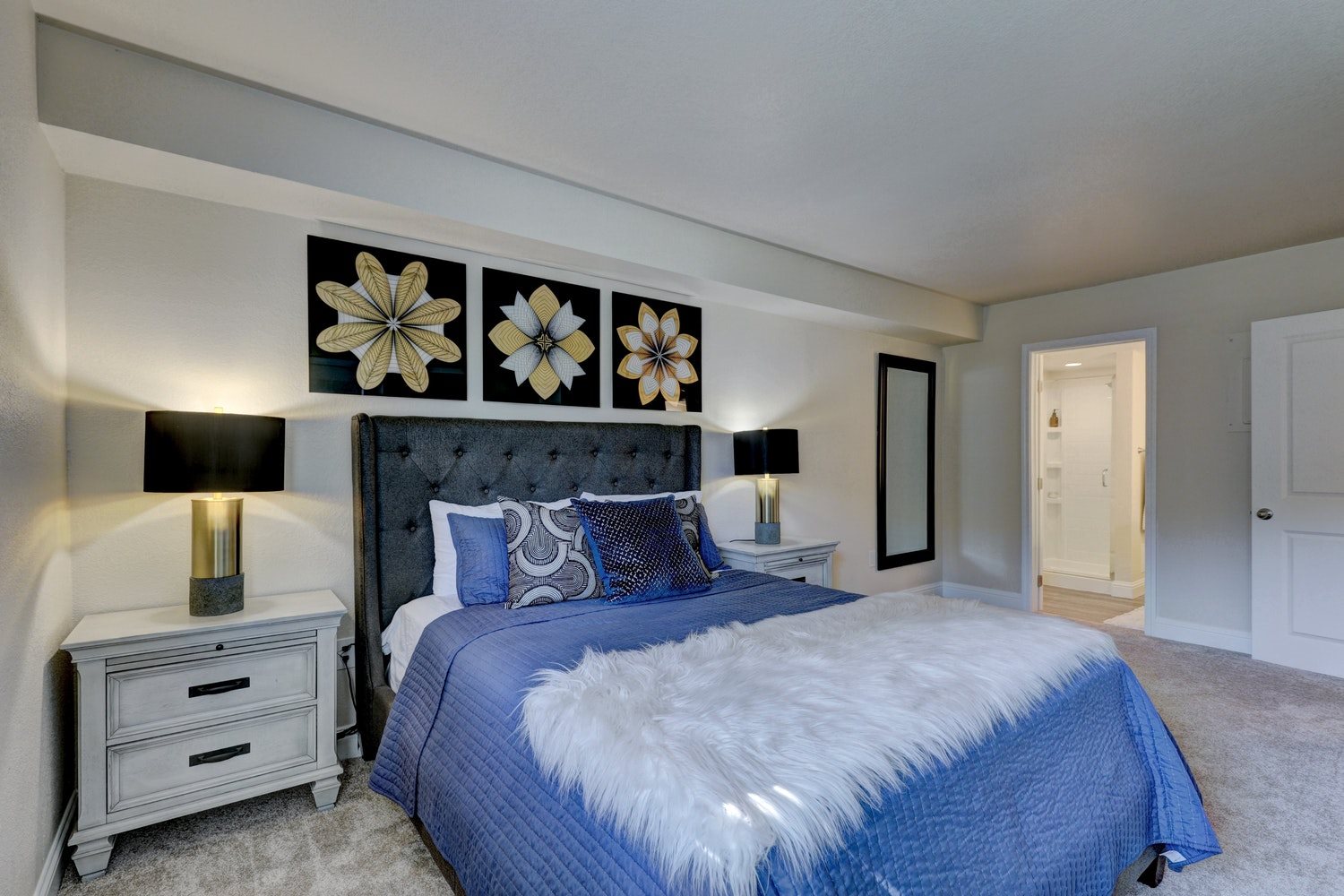 A bedroom with a large bed and a white fur throw.